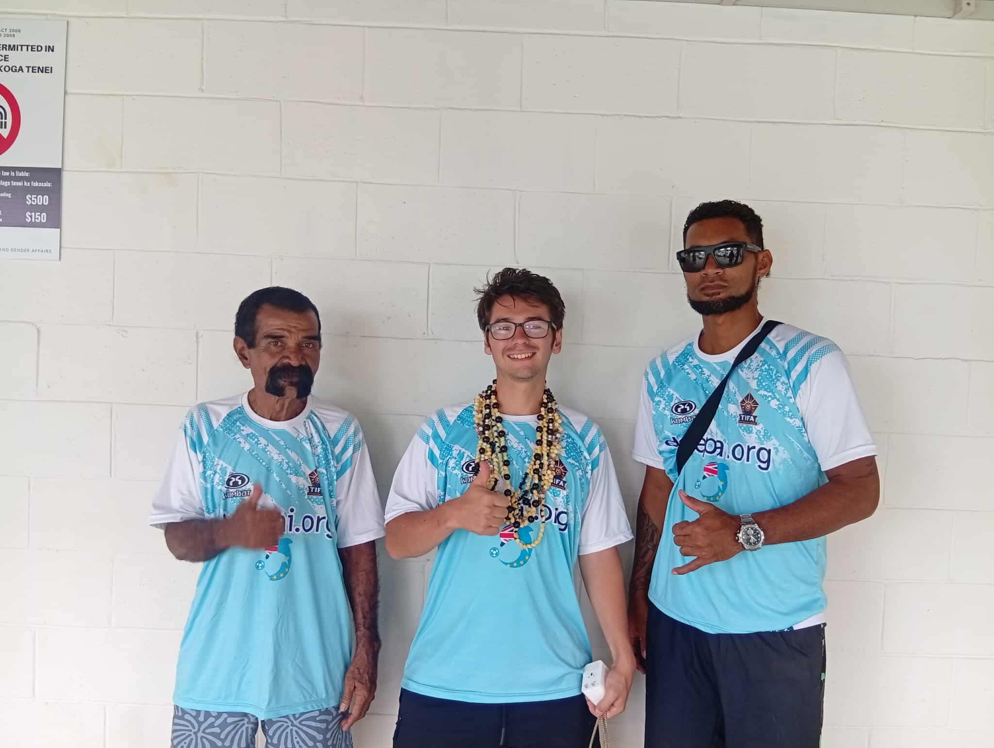Nick Miller standing with two local football community members in matching shirts.